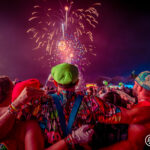 Three people dressed in mario and luigi outfits looking at fireworks