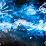 Blue lights and lasers creating a cloud in the sky at Music Festival 2023