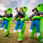Three men wearing inflatable dinosour outfits at Imagine Music Festival 2023