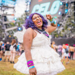 Black women with purple hair wearing white dress at Imagine Music Festival 2023