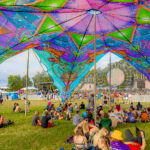 Festival-goers sitting under a psychadelic canopy at Imagine Music Festival 2023
