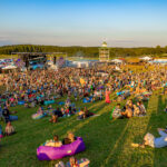 Festival crowd sitting and standing on a grassy hill at Imagine Music Festival 2023